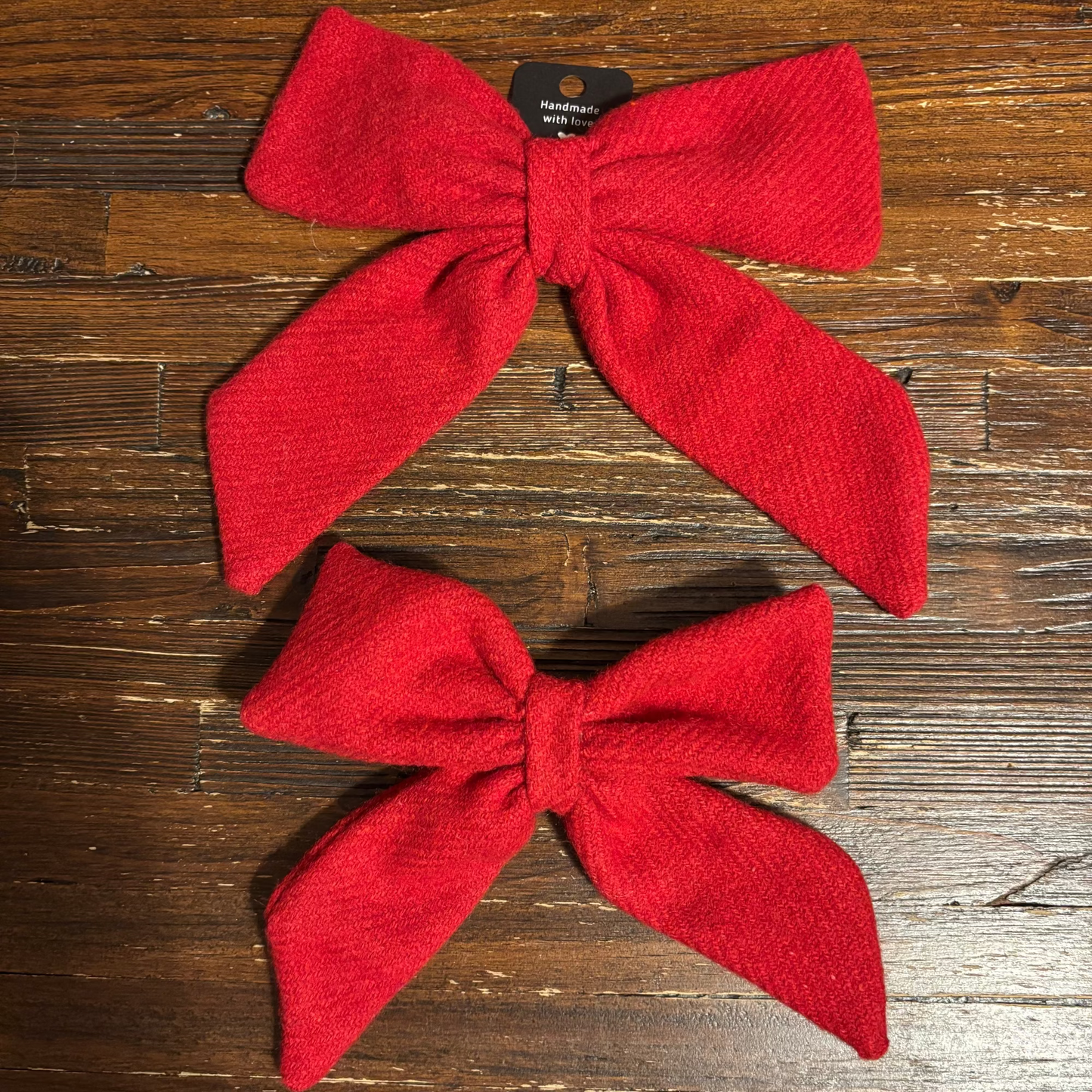 Two red bows on a wooden surface