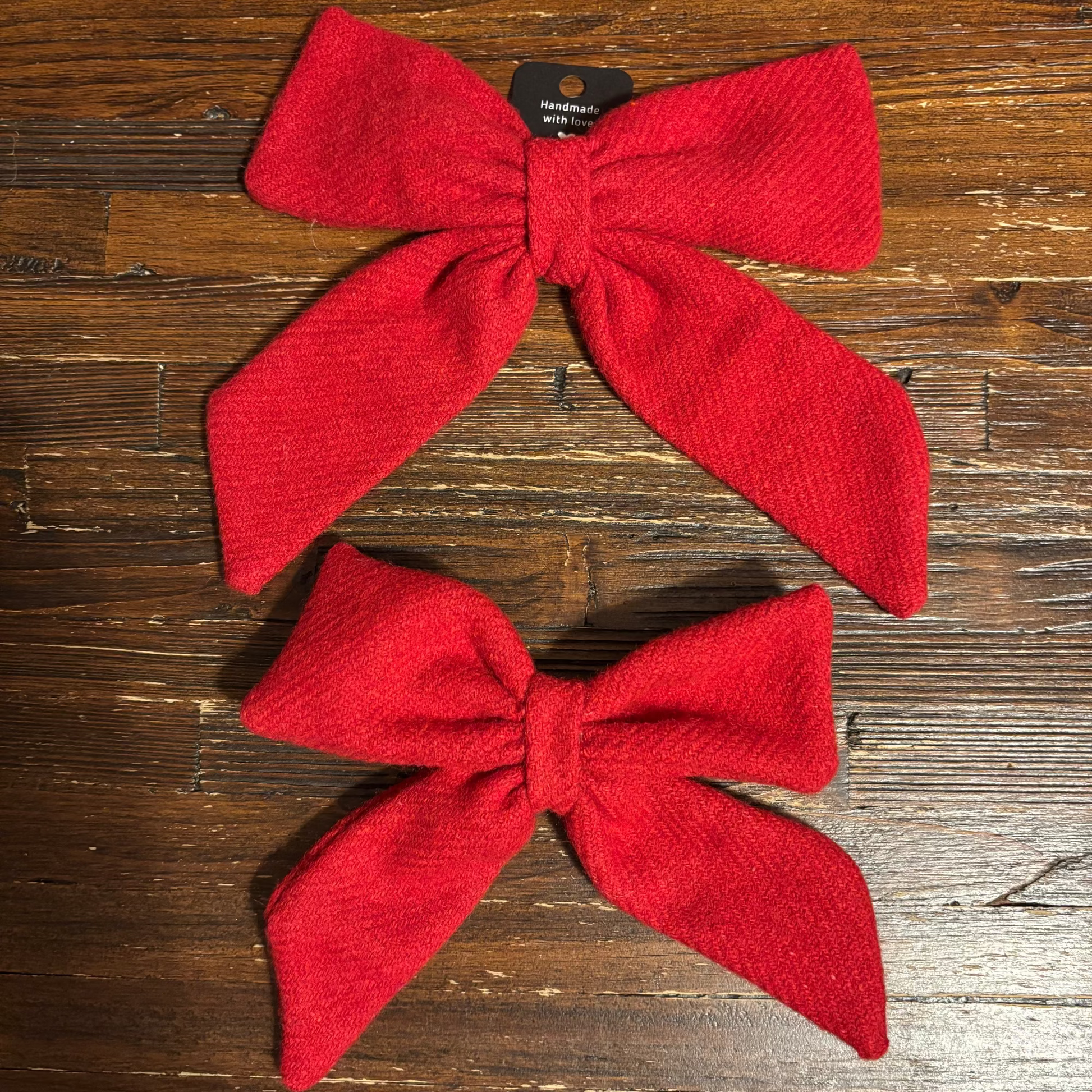 Two red bows on a wooden surface
