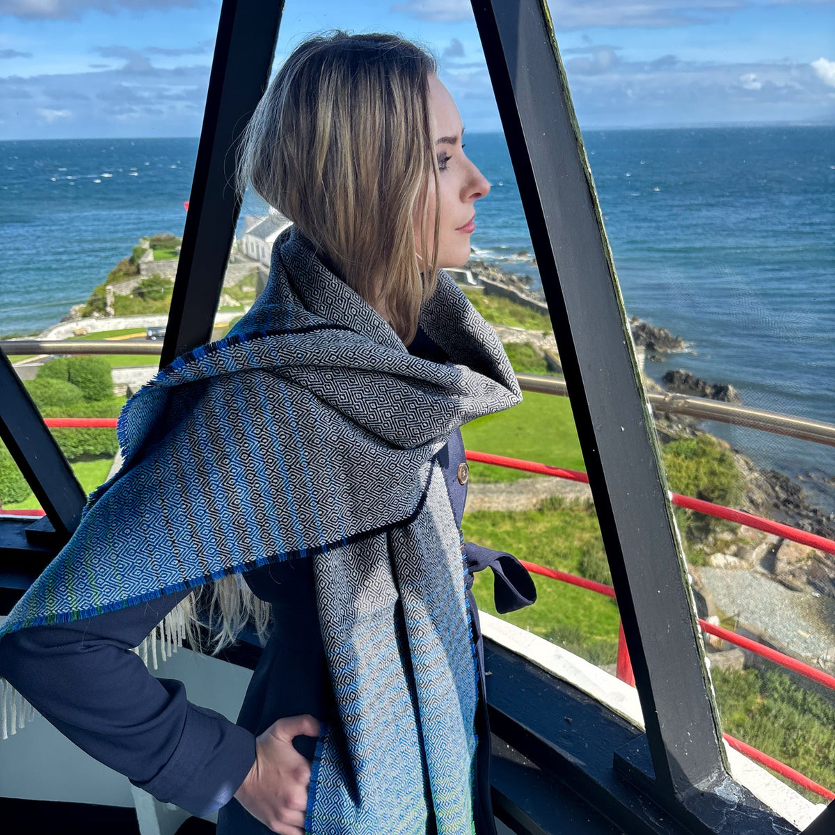 women stands in lighthouse on donegal Ireland coastline wearing tweed