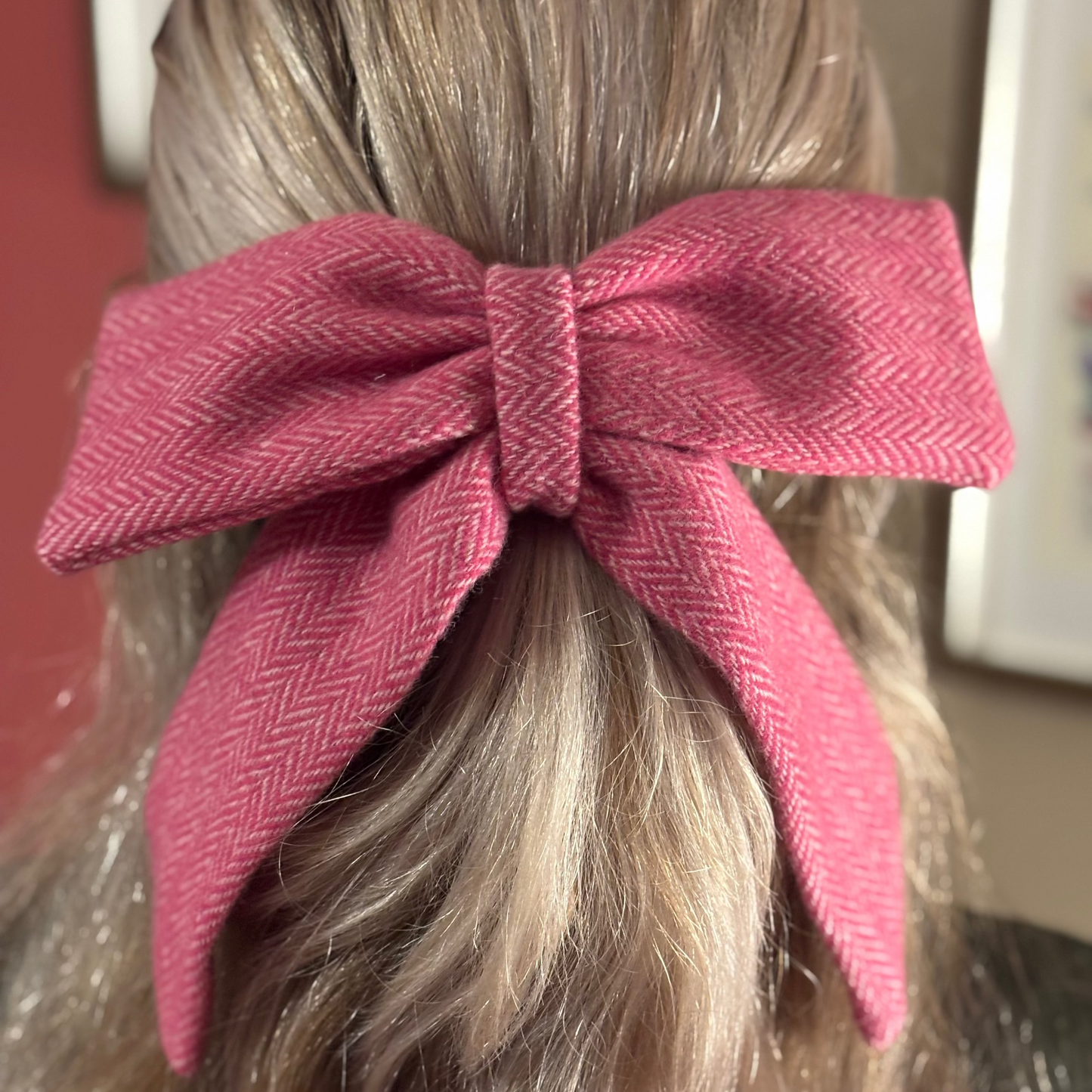 Close-up of a pink donegal tweed bow in a person's hair with a blurred background