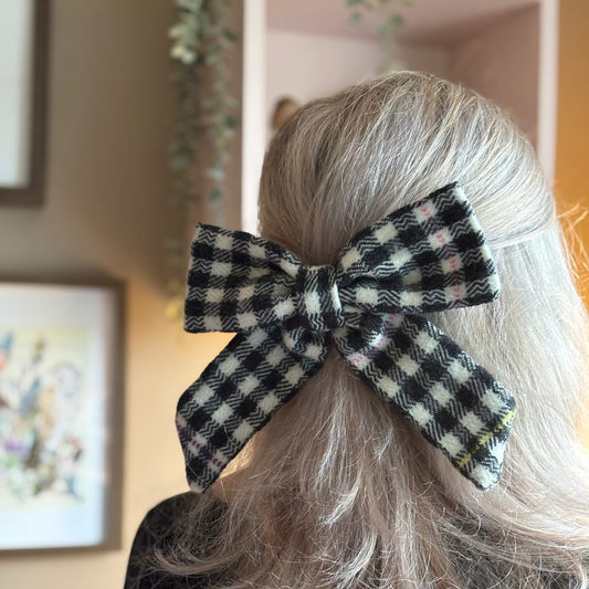 Person with checkered Tweed bow in hair against a neutral background