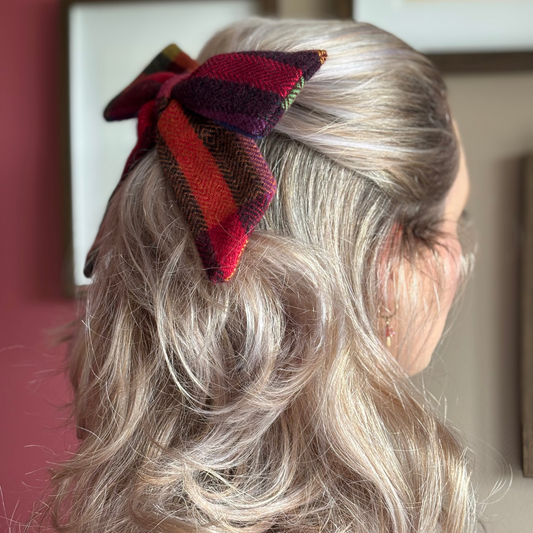 Person with a colorful Irish Tweed bow in their hair, standing in a room with framed pictures on the wall.