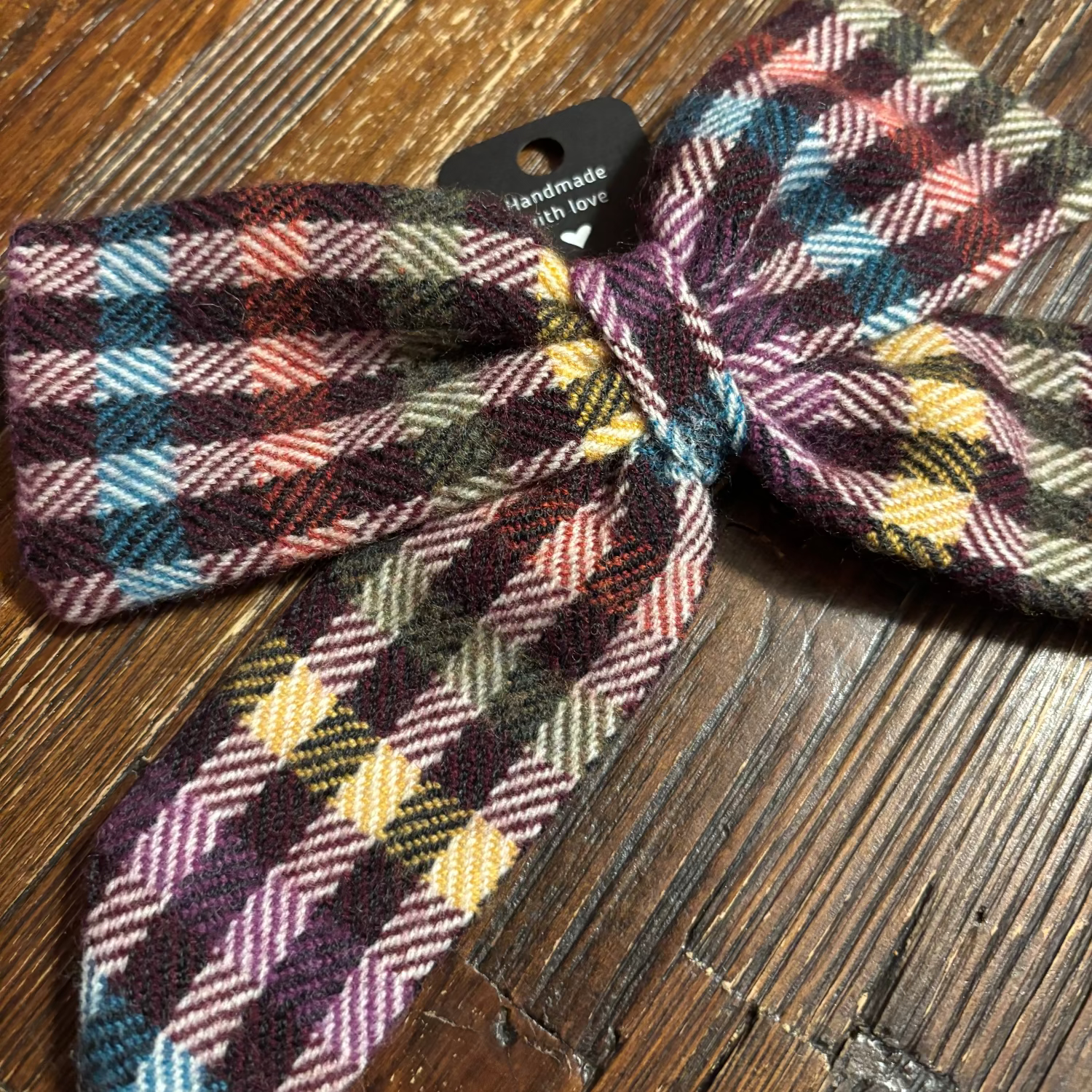 Plaid Tweed bow tie on a wooden surface with a visible brand tag.