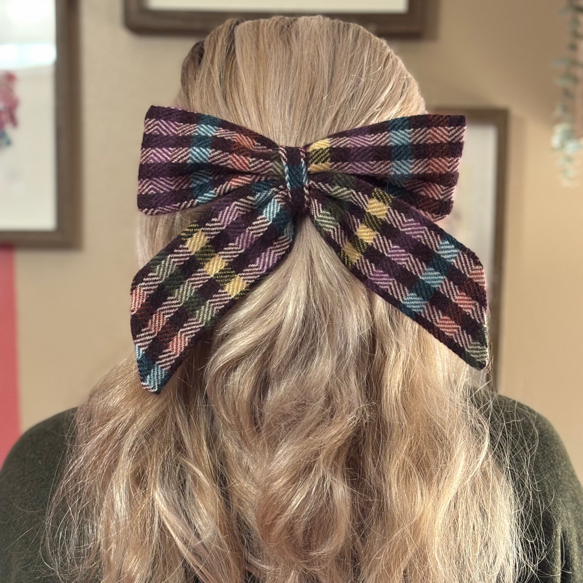 Person wearing a large, colorful bow in their hair with a neutral background