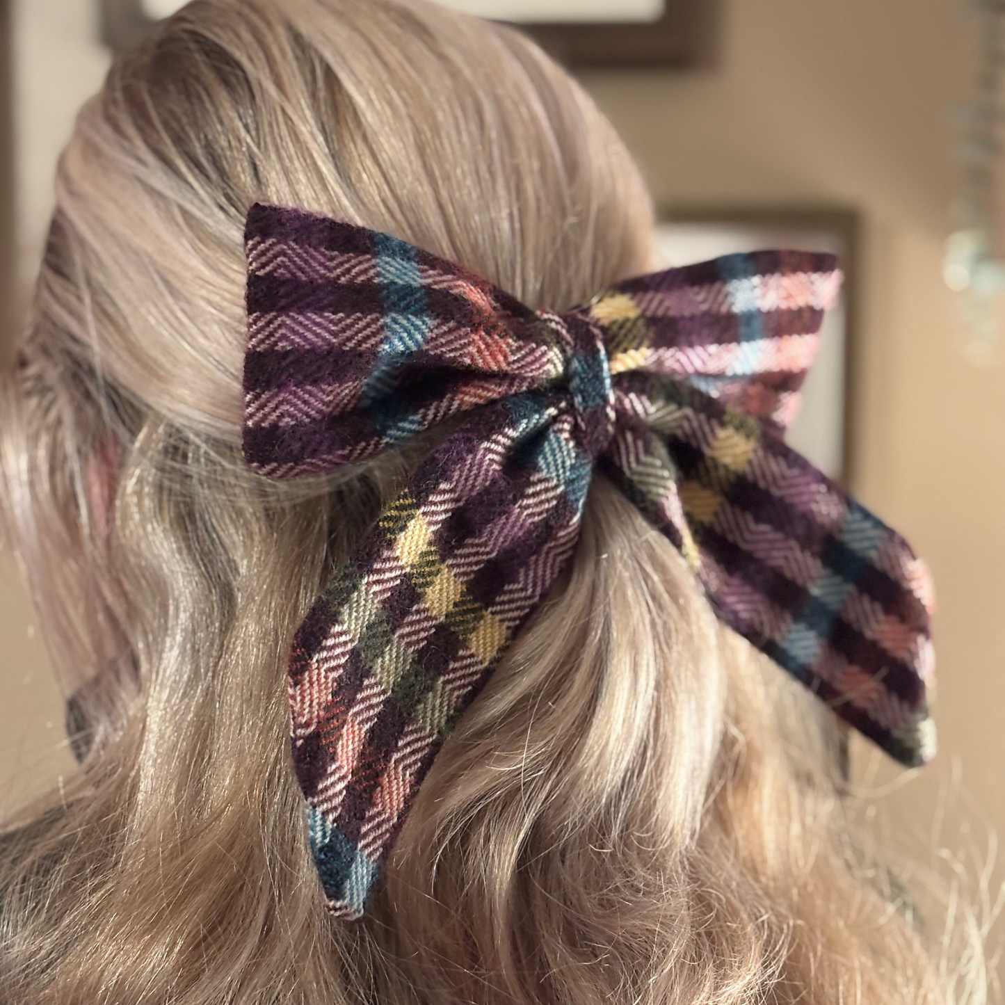 Plaid hair bow on a person's head with wavy hair.
