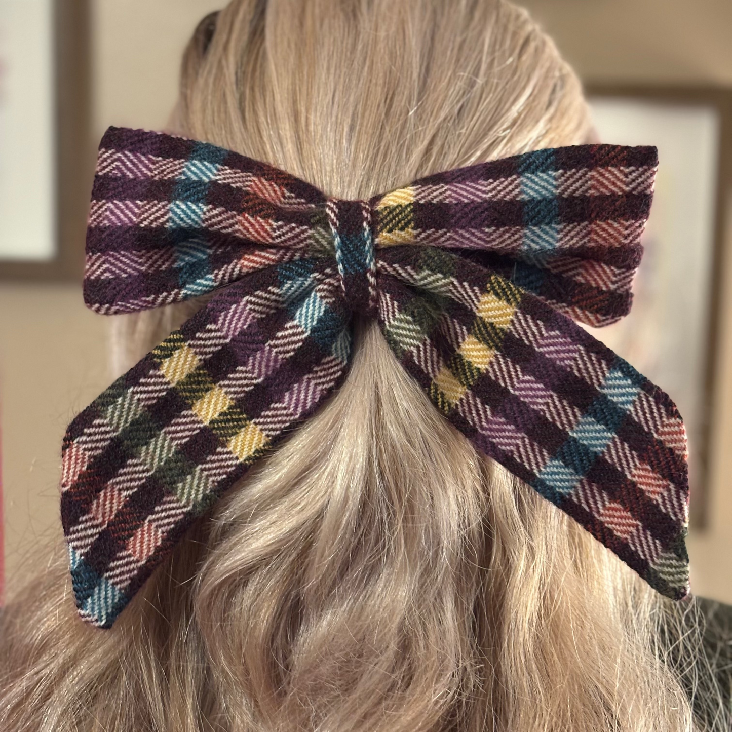 Plaid hair bow on a person's head with a neutral background