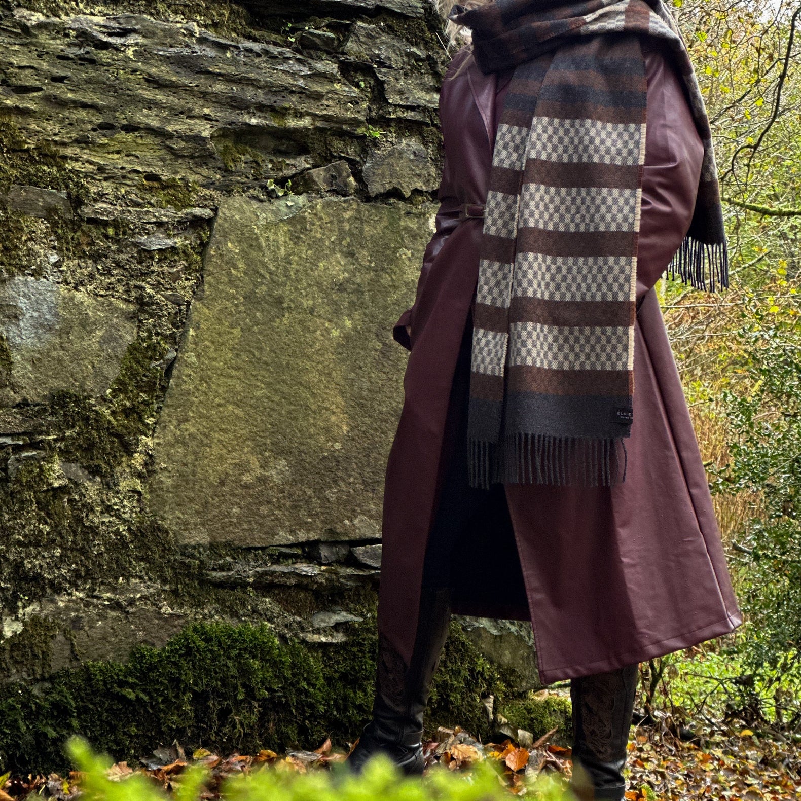 Person wearing a long coat and scarf in a forest setting