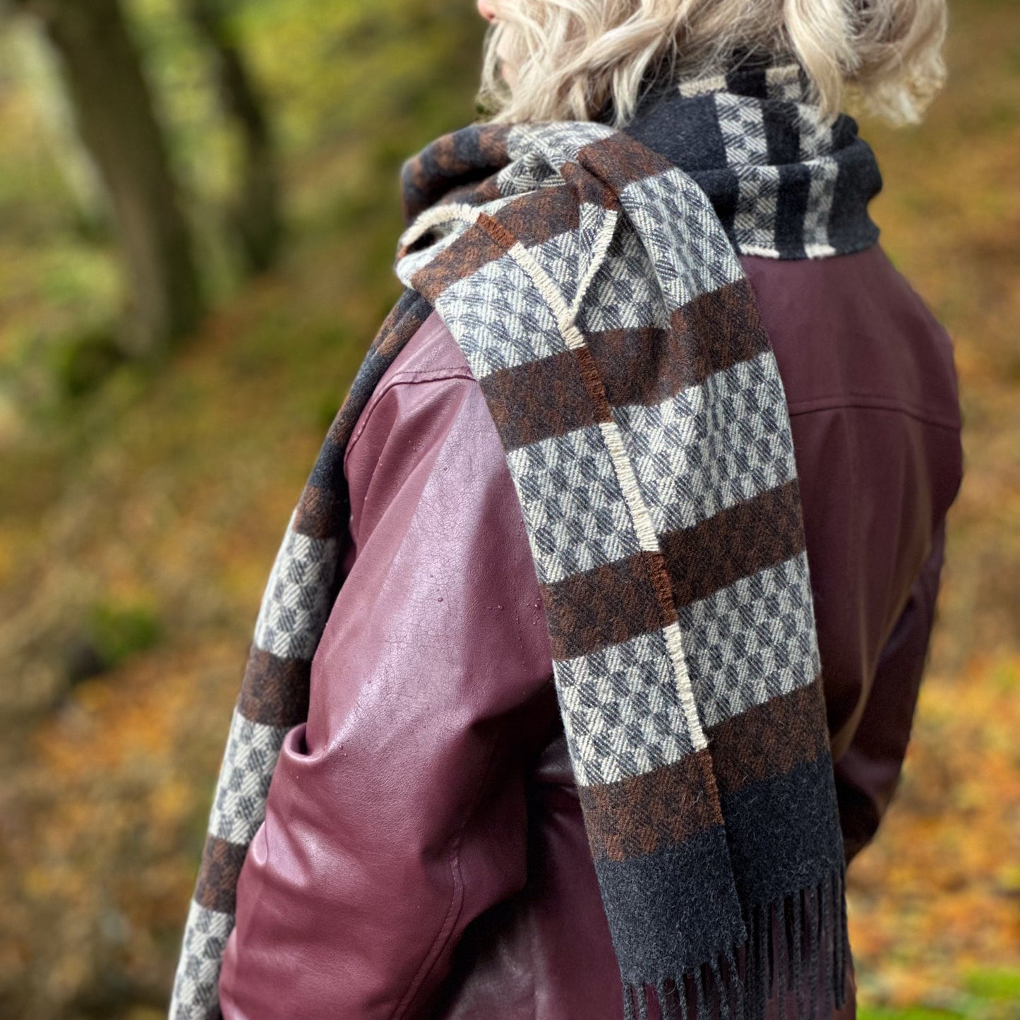 Person wearing a plaid donegal tweed scarf in an autumn setting
