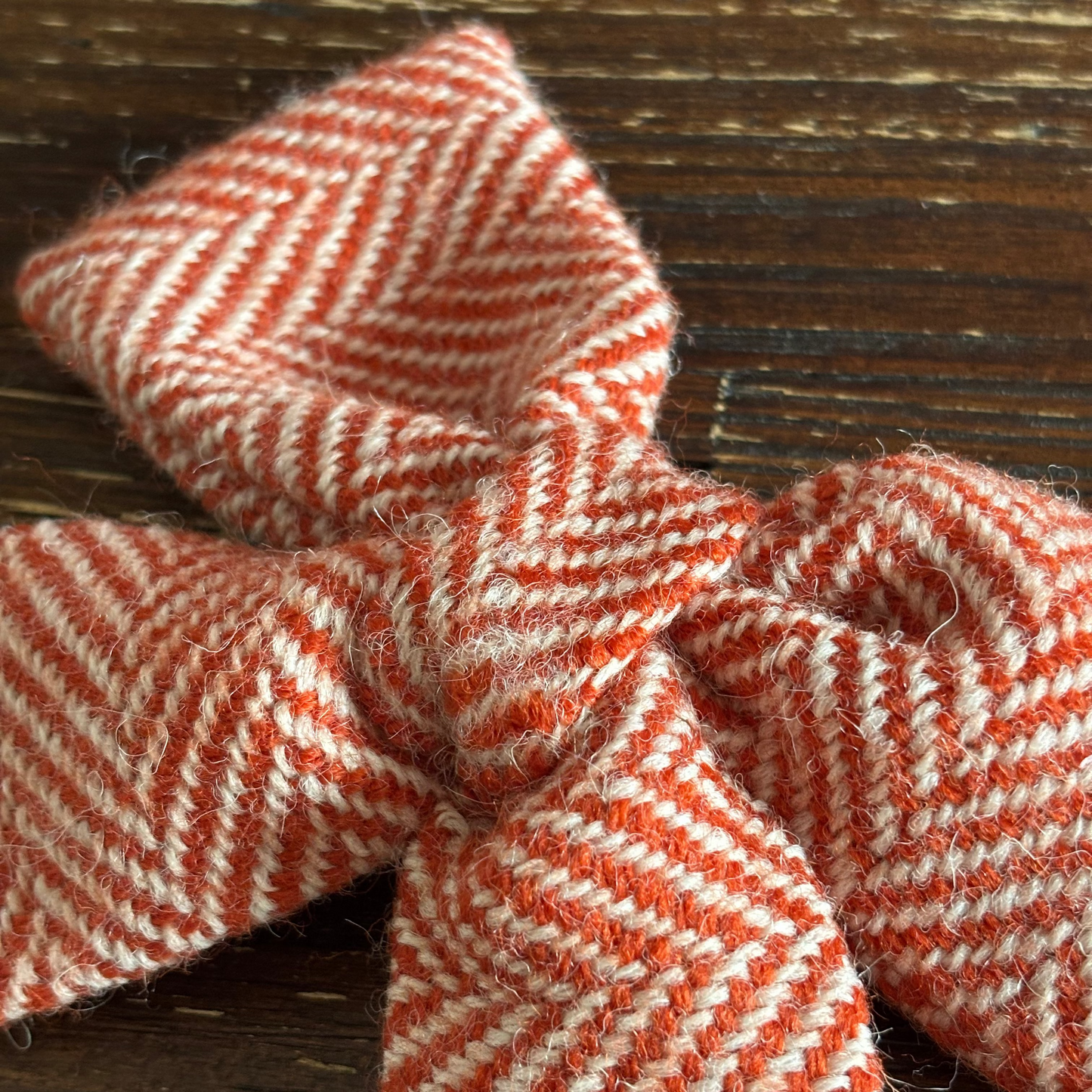 orange and white herringbone tweed bow  on a wooden surface