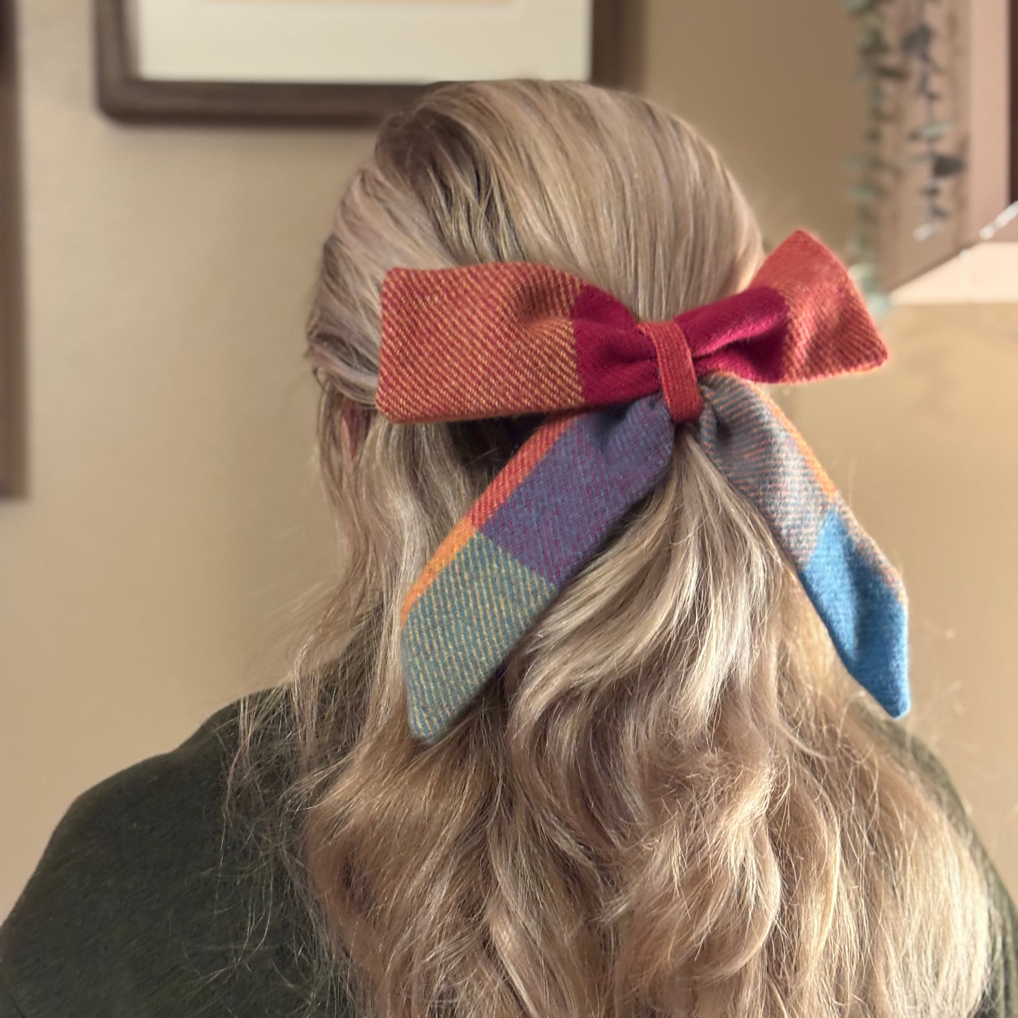 Person with a colorful bow in their hair, wearing a dark green sweater.