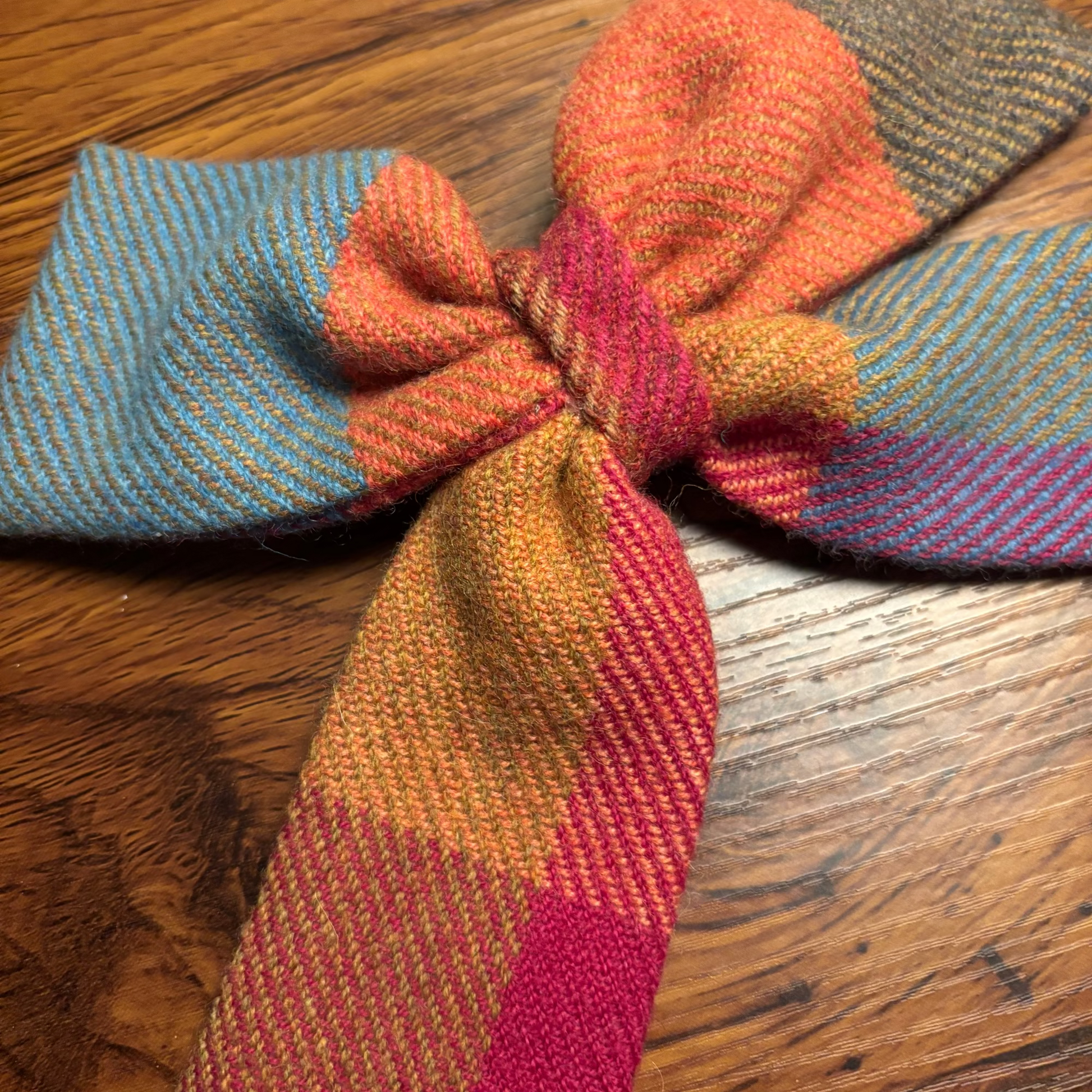 Knitted bow tie with multicolor pattern on a wooden surface
