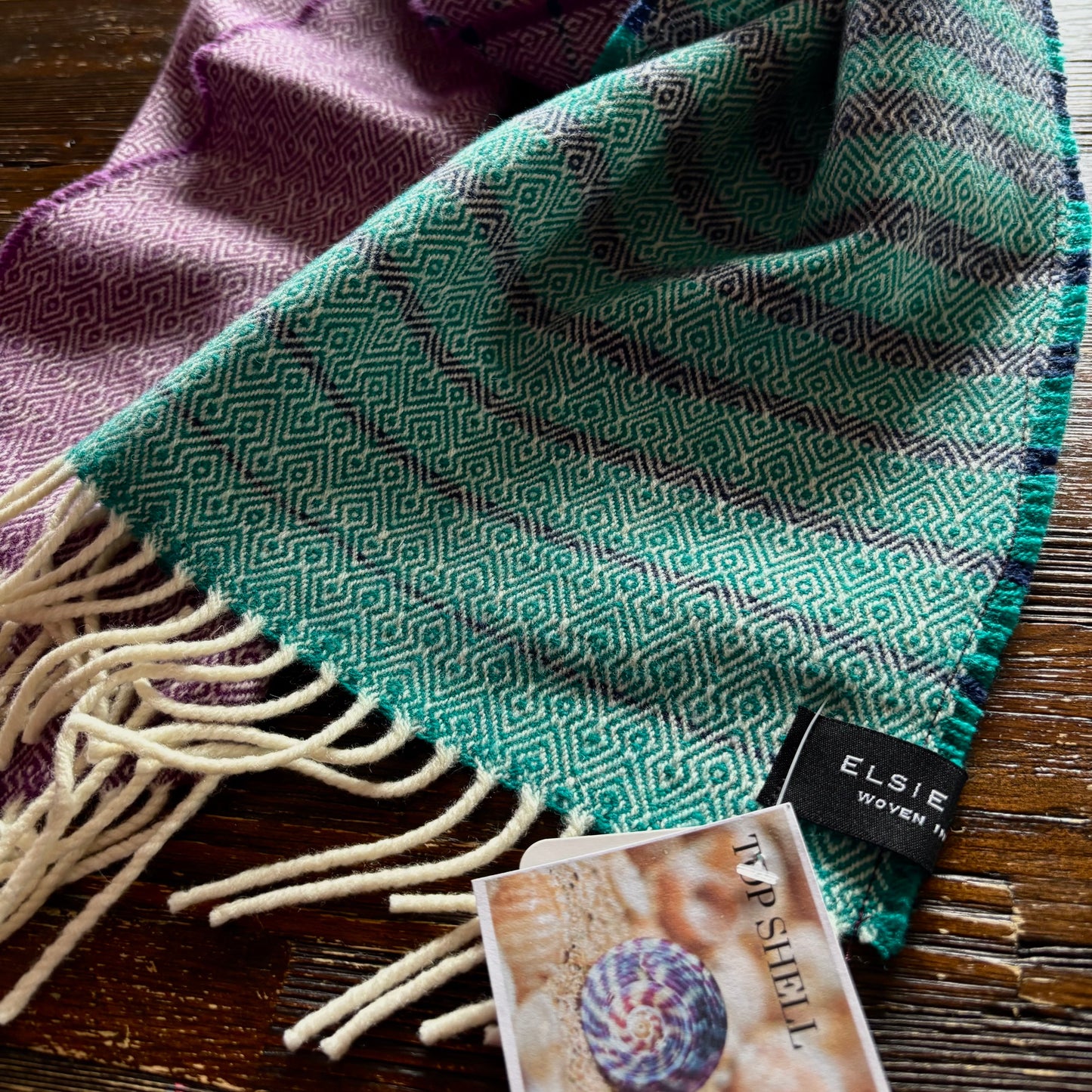 Two patterned scarves with a visible brand tag on a wooden surface