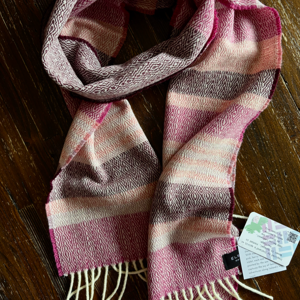 donegal tweed scarf with pink, plum, and peach  colours on a wooden surface