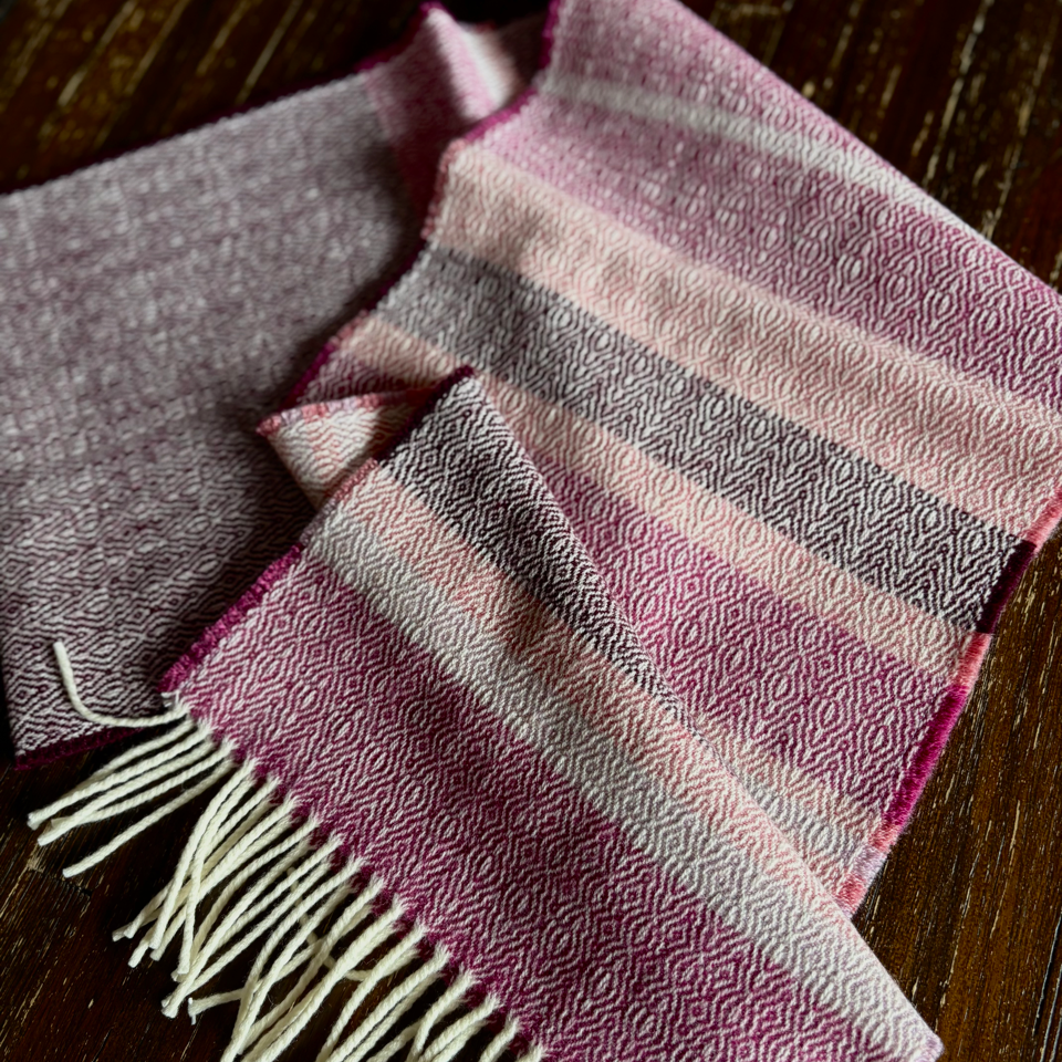 Folded striped donegal scarf  with fringes on a wooden surface